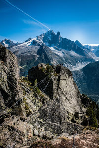 Aerial view of snowcapped mountains against blue sky