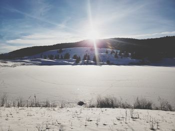 Scenic view of snow covered landscape against bright sun