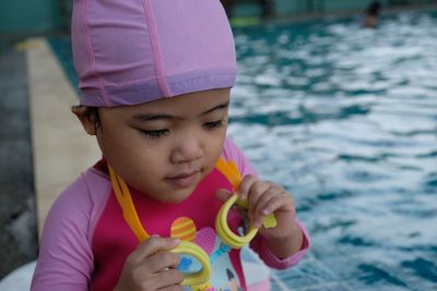 Cute girl looking down while sitting by swimming pool