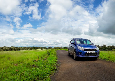 Car on road by land against sky