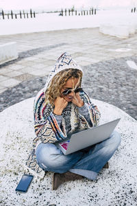 Woman using laptop while sitting outdoors