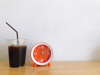 Close-up of clock on table against wall