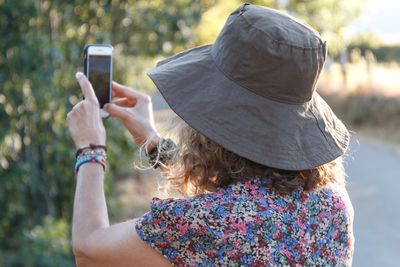 Rear view of woman photographing with mobile phone