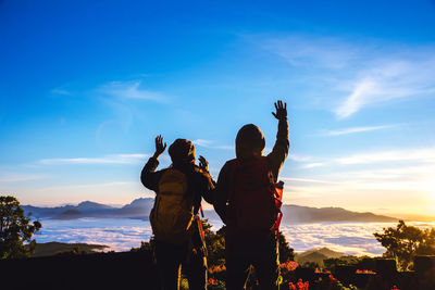 Rear view of people standing on mountain against sky