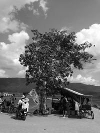 People sitting in park against sky in city