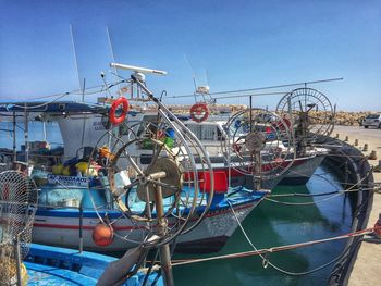 Fishing boats moored at harbor against clear blue sky