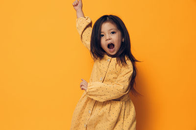 Portrait of young woman standing against yellow background