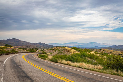 Road leading towards mountains against sky