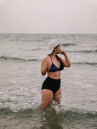 Woman standing at beach against sky