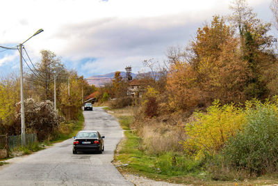 Cars on road against sky during autumn