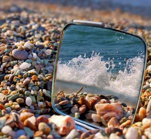 Close-up of mirror on pebbles at beach