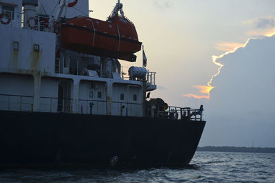 Boat sailing in sea against sky during sunset