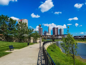 Empty road by river leading towards city