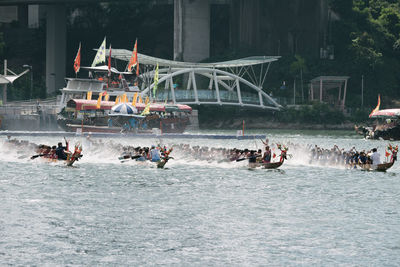Group of people in sea against built structure