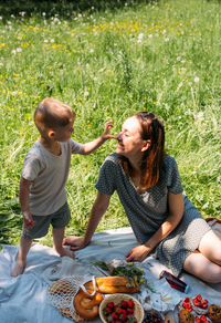 Family mom and son on picnic. smiling and enjoying summer on blanket in park.