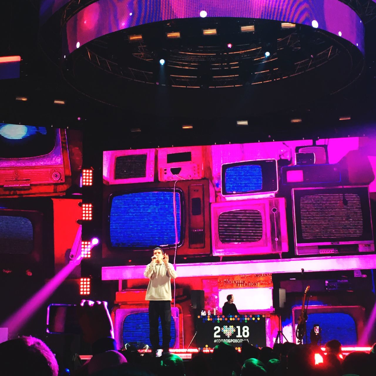 REAR VIEW OF PEOPLE STANDING IN ILLUMINATED STAGE