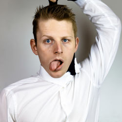 Close-up portrait of young businessman committing suicide against gray background