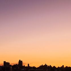 Silhouette buildings against clear sky during sunset