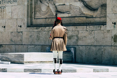 Rear view of woman standing against wall