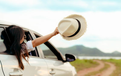 Portrait of woman on car against sky