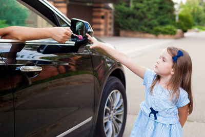 Cropped hand of person giving chocolate to girl standing on road