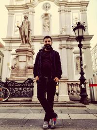 Portrait of young man standing against historic building