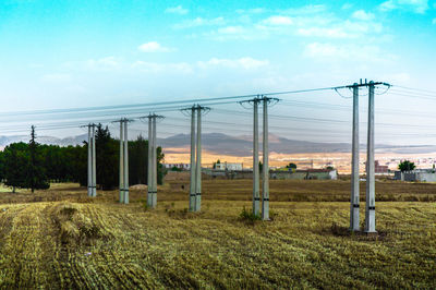 Electricity pylon on field against sky