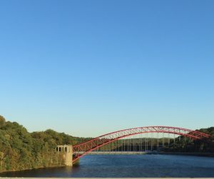 Bridge over river against clear blue sky