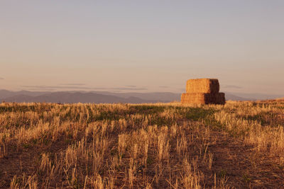 Hay bales on field against sky during sunset