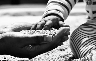 Midsection of baby touching grains in hand