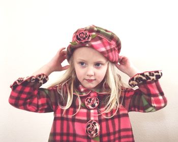 Girl wearing hat standing against wall