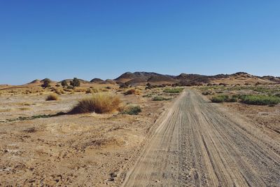 Scenic view of arid landscape against clear blue sky