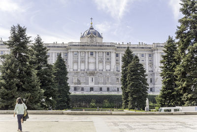 Rear view of woman walking against madrid royal palace