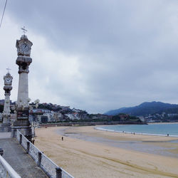 View of buildings by sea against cloudy sky