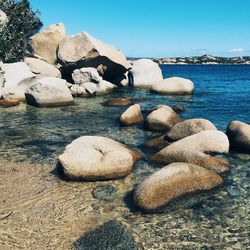 Pebbles on beach against clear sky