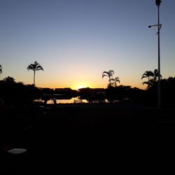 Silhouette palm trees against clear sky during sunset