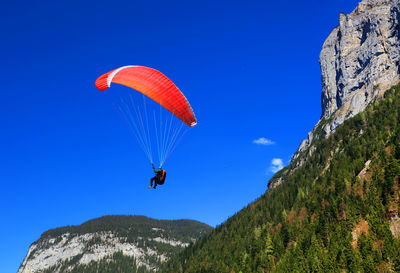 Low angle view of person paragliding against clear blue sky