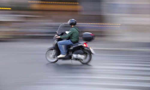 Side view of man riding motorcycle on road