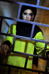 Portrait of woman standing by metal grate