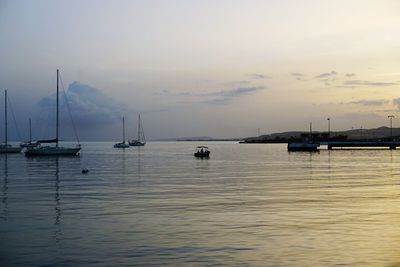 Boats sailing in sea against sky during sunset