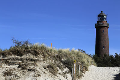 Lighthouse by sea against sky