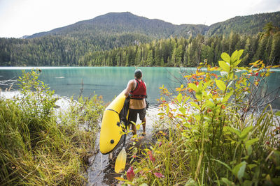 Man carries inflatable packraft (kayak) into cheakamus lake, whistler.