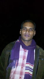 Portrait of young man standing against black background