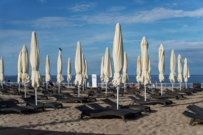 Parasols and lounge chairs at beach against sky