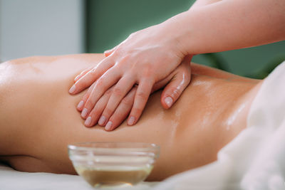 Massaging with massage oil, hands of a female massage therapist massaging a female client