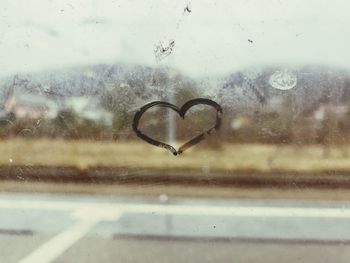 Close-up of wet window against sky