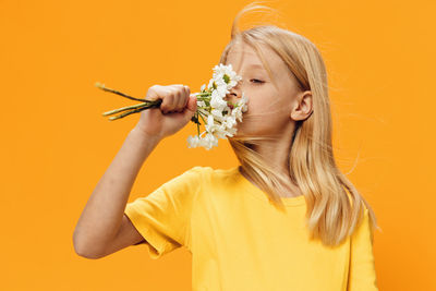 Girl smelling flowers against orange background