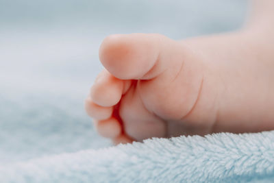 Foot with toes of a sleeping caucasian newborn baby lying in bed on a blue fleece blanket, side view