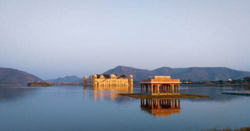 Built structure on lake by mountains against clear sky