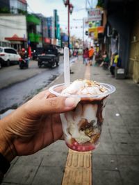 Hand holding ice cream cone on street